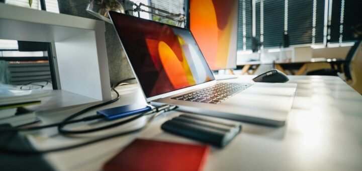 A modern workspace featuring a laptop, external drives, and office equipment on a desk.
