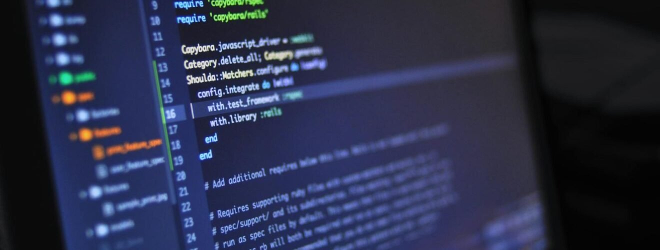 Close-up of a computer screen displaying programming code in a dark environment.