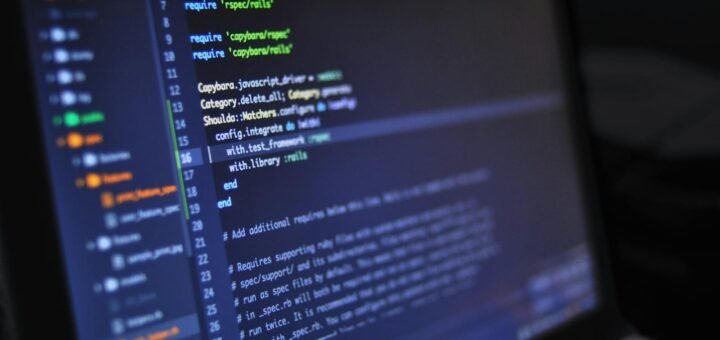 Close-up of a computer screen displaying programming code in a dark environment.