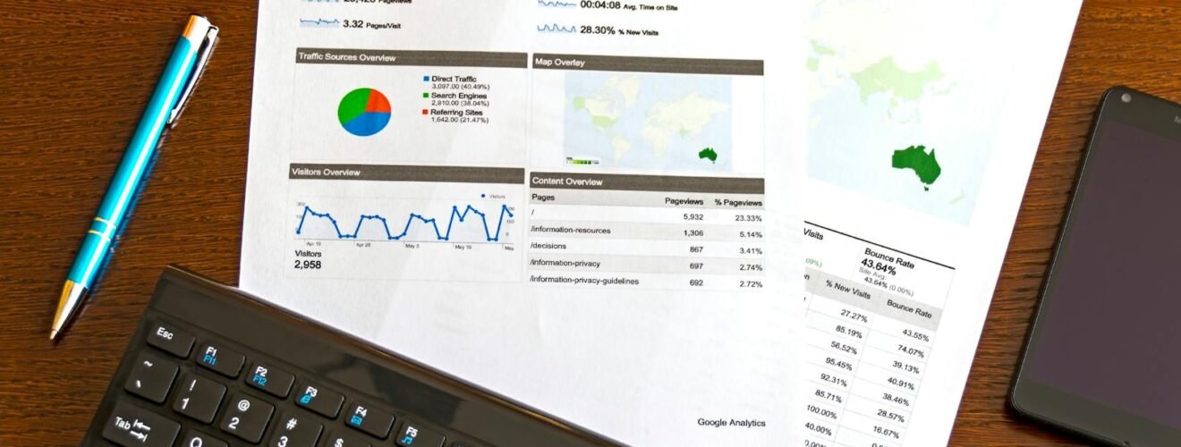 Flatlay of a business analytics report, keyboard, pen, and smartphone on a wooden desk.