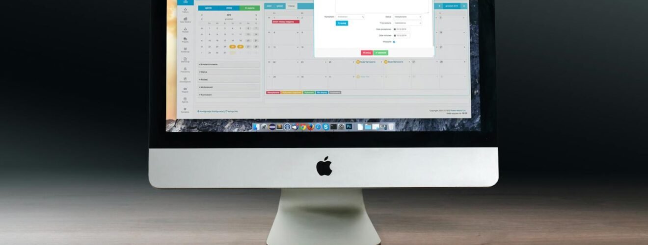 A sleek office setup featuring an Apple iMac, iPad, and keyboard on a wooden desk.