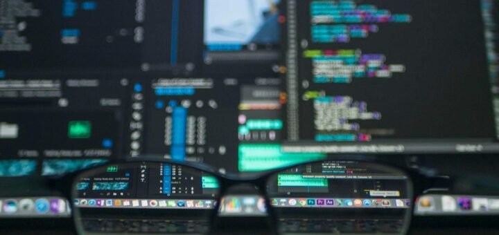 Eyeglasses reflecting computer code on a monitor, ideal for technology and programming themes.