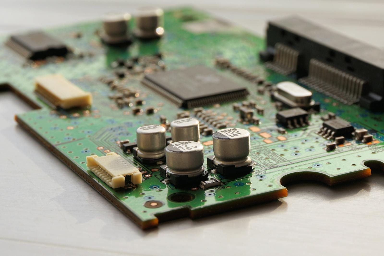 Detailed view of a green circuit board featuring capacitors and microchips.