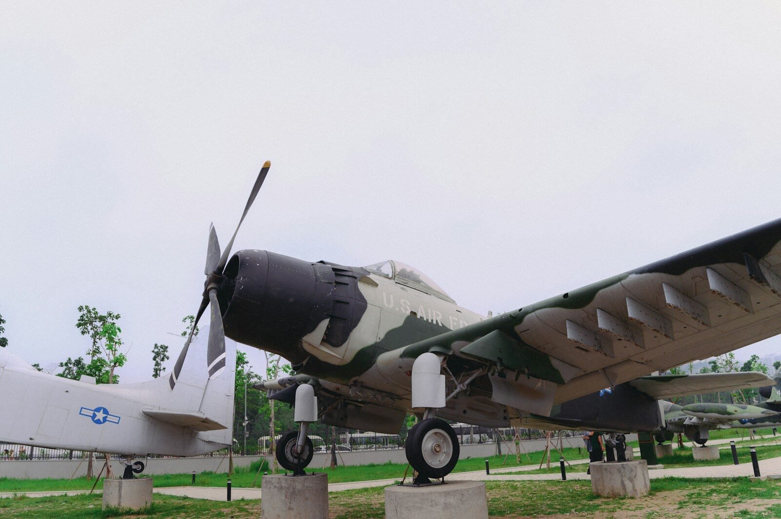 A camouflaged airplane is displayed outdoors.