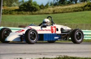 Race car speeding at Elkhart Lake track, Wisconsin, showcasing motorsport action.