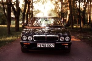 A luxurious sedan parked on a scenic pathway surrounded by trees in Minsk, Belarus.