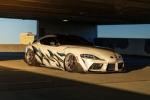 Custom sports car with artistic decals in a sunlit urban parking garage.