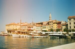 Sunny harbor with traditional boats and colorful old buildings.