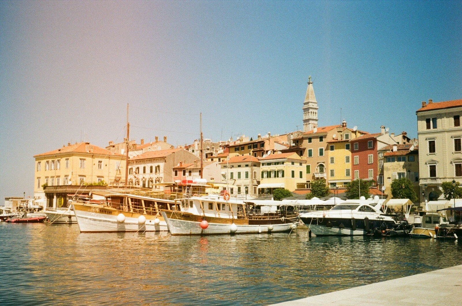 Sunny harbor with traditional boats and colorful old buildings.