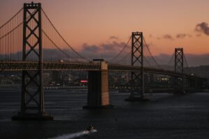 The Bay Bridge spanning the water in San Francisco under a warm orange sky