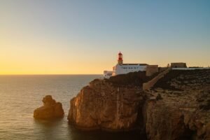 The Cabo de São Vicente lighthouse on a rocky cliff above the ocean at golden hour