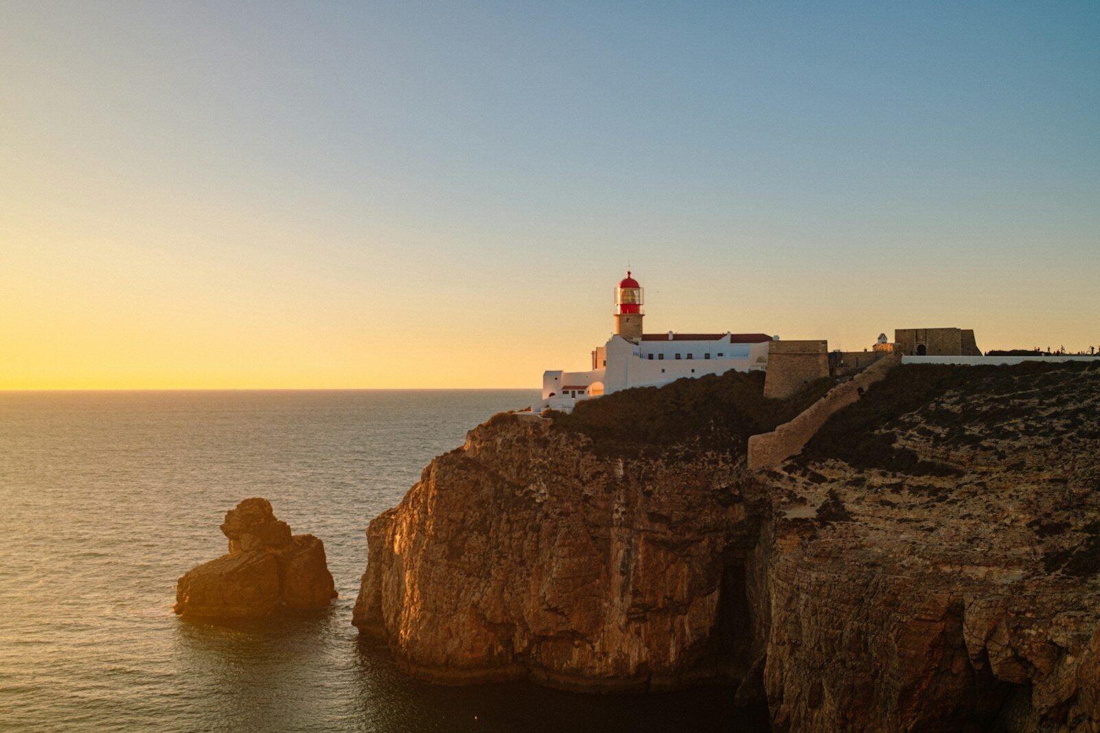 The Cabo de São Vicente lighthouse on a rocky cliff above the ocean at golden hour